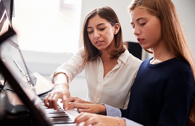 piano teacher and student
			sitting at a piano